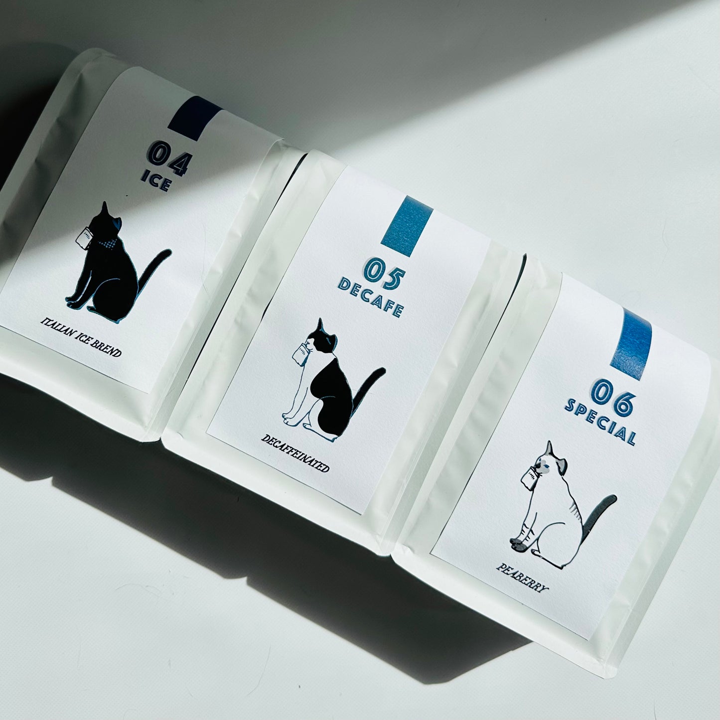 黒猫、ハチワレ猫、雑種シャム猫のパッケージに入った３袋のコーヒー豆